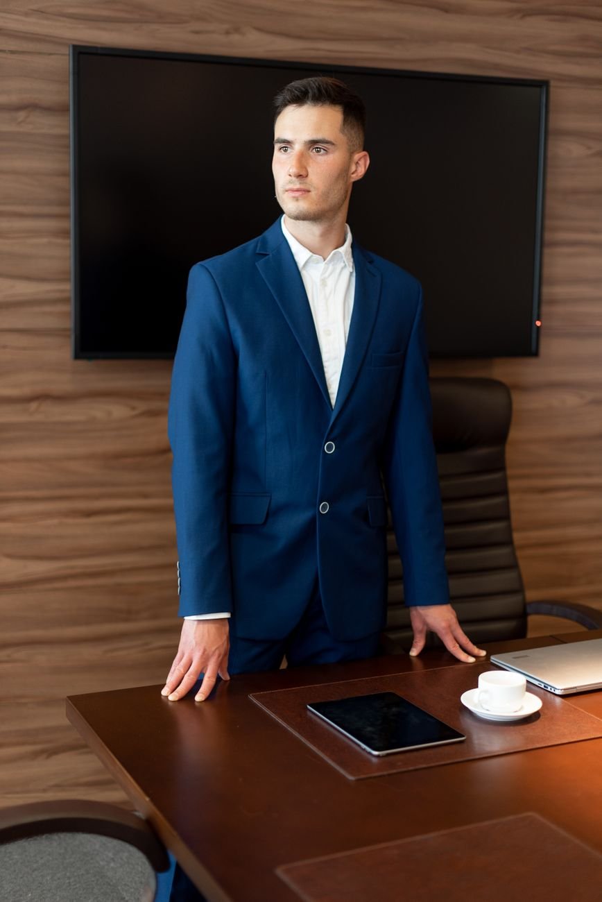 Professional man in a blue suit standing confidently in a modern office.